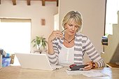 Woman working at home office with computer and bills