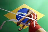 Runner Breaking through the finishing line tape over Brazilian flag