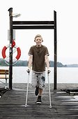 Portrait of boy holding crutches while standing on one leg
