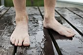 Low section of wet barefoot on wooden floor