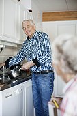 Senior man washing utensil while looking at wife