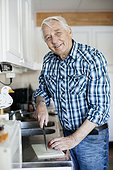 Portrait of smiling senior man with knife in kitchen