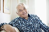 Portrait of smiling elderly man sitting in living room