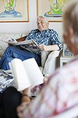 Senior man and woman reading newspaper and book in living room