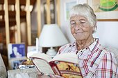 Happy senior woman reading novel in loving room