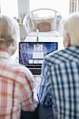 Active senior couple using laptop together in living room