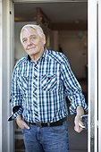 Portrait of elderly man standing with hands in pocket at door