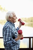 Side view of senior adult man lifting hand weight outdoors