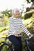 Happy senior woman cycling in park
