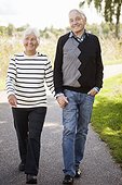 Front view of senior couple holding hands walking in park