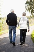 Rear view of active senior couple walking in park