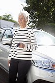 Senior woman standing in front of car holding key