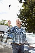 Senior man tossing car key in air