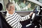 Cheerful senior woman sitting on driver seat in car