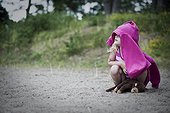 Girl shading her head with pink jacket on sandy beach