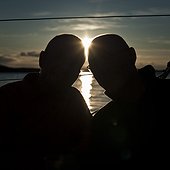 Silhouette image of two males with sun in background