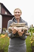Portrait of cheerful woman with firewood in back yard