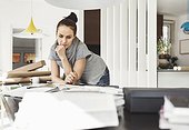 Thoughtful female architect leaning on table at home office
