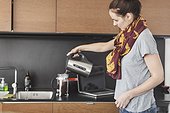 Side view of woman preparing coffee in kitchen