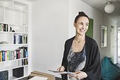Happy female architect holding book in home office