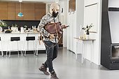 Full length of male architect with bag using mobile phone while walking in kitchen