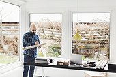 Male architect working at table in home office by window