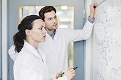 Scientists discussing plan on whiteboard in laboratory