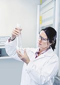 Female scientist scrutinizing chemical in beaker at laboratory