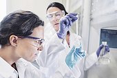 Female scientists examining chemical in laboratory