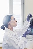 Side view of female scientist using pipette while examining chemical in laboratory