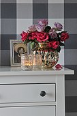 Bunch of roses, photograph and candles on dresser