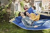 Happy family playing in hammock in garden of their home