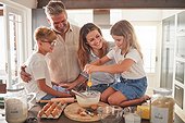 Happy family cooking or baking in kitchen together with mother, father or parents and children learning for love, care and support. Dad, mom and kids with food, eggs and flour for morning breakfast