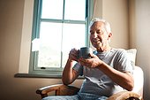 Hmm, nothing like a cup of coffee in the morning. a happy senior man holding a cup of coffee and sitting in an armchair at home.