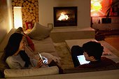 Couple using smart phone and digital tablet in dark living room