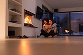 happy multiethnic couple sitting in front of fireplace