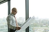 Businessman in office looking at blueprint