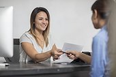 Smiling woman handing over pen to client at desk