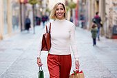 Cheerful woman with shopping bags on street