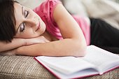 portrait of young woman sleeping on sofa with book