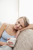portrait of young woman with coffee cup relaxing on sofa