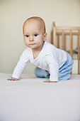 portrait of young baby boy crouching on floor