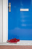 pair of red sneaker at door outside apartment