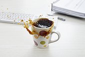 still life of coffee spilling out of cup on desk