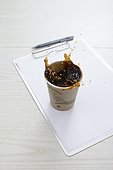 still life of coffee spilling out of paper cup on desk