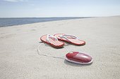 pair of flip flops and computer mouse on sandy beach