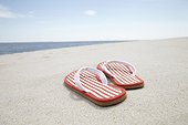 pair of flip flos on sandy beach