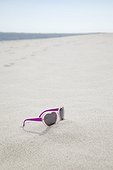 heart shaped sunglasses on sandy beach