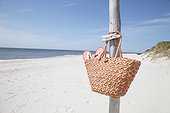 basket with flip flops hanging on pole at beach