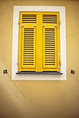 bright yellow shutters on a pale yellow wall; italy